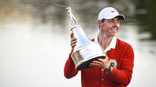 Rory McIlroy of Northern Ireland smiles and holds the tournament trophy while wearing a replica Arnold Palmer red cardigan following his three stroke victory on the 18th hole green in the final round of the Arnold Palmer Invitational presented by MasterCard at Bay Hill Club and Lodge on March 18, 2018 in Orlando, Florida.