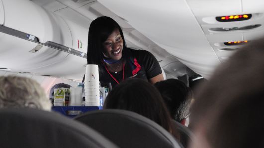 An American Airlines flight attendant serves drinks to passengers after departing from Dallas/Fort Worth International Airport in Texas.