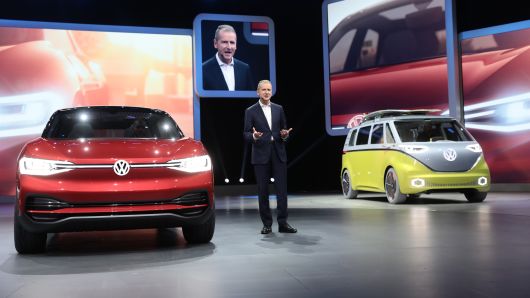 Herbert Diess, head of the Volkswagen AG (VW) brand, speaks while flanked by a VW I.D. Crozz concept electric automobile, left, and an I.D. Buzz camper van during the first media preview day of the IAA Frankfurt Motor Show in Frankfurt, Germany, on Tuesday, Sept. 12, 2017. 