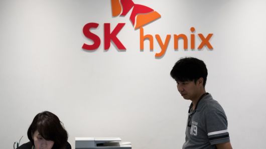Employees stand in front of the SK Hynix Inc. logo displayed at the company's office in Seongnam, South Korea, on Monday, July 24, 2017.