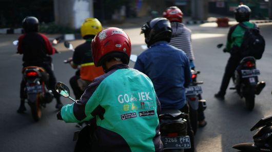 A Go-Jek motorcycle taxi driver travels through traffic in Jakarta, Indonesia, on Saturday, Aug. 4, 2018.