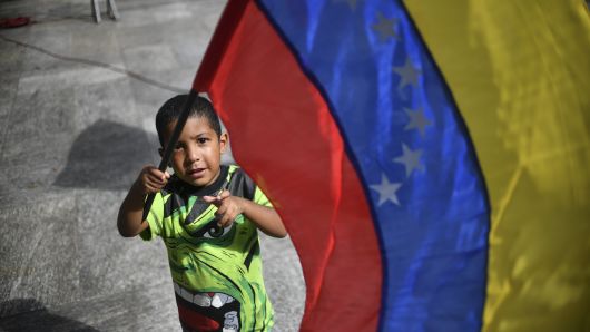 A boy waves a Venezuelan national flag, as supporters of Venezuelan President Nicolas Maduro gather at Bolivar square in Caracas to take part in a signature campaign to urge the United States' to put a halt to intervention threats against Maduro's government, on February 6, 2019.