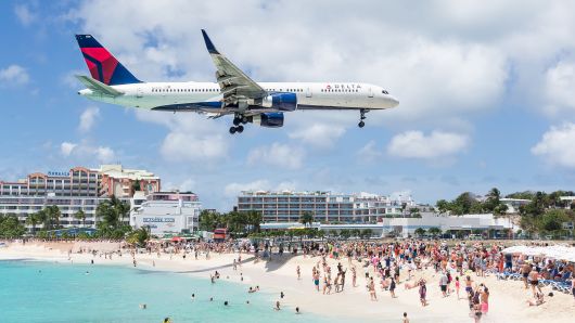 An airplane flying just above beachgoers in Maho Beach as it approaches the landing strip in St. Maarten, 30 March 2016.