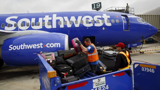 Ground operations employees load baggage onto a Southwest Airlines Co. Boeing Co. 737 aircraft on the tarmac at John Wayne Airport (SNA) in Santa Ana, California, U.S., on Thursday, April 14, 2016.