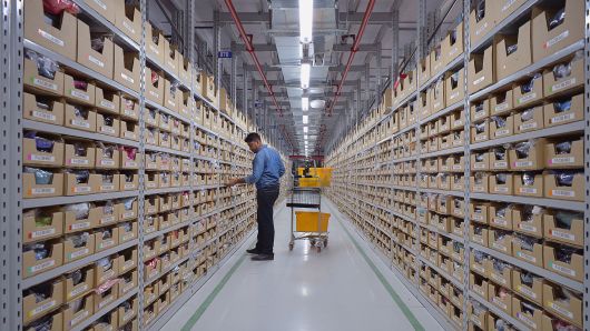 An employee of Amazon India retrieves products from an assorted storage area to fulfil orders placed by customers prior to packaging at Amazon's newly launched fulfilment centre on the outskirts of Bangalore on September 18, 2018.