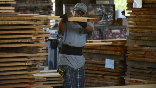 A worker carries a Heart Pine plank of lumber in the sawmill at the Goodwin Co. facility in Micanopy, Florida.