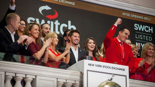 Rob Roy, founder and chief executive officer of Switch Inc., center, rings the opening bell before the company's initial public offering (IPO) on the floor of the New York Stock Exchange (NYSE) in New York, Oct. 6, 2017.