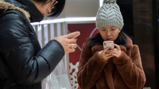 A woman uses an Apple iPhone inside a shopping mall in Beijing on January 3, 2019.