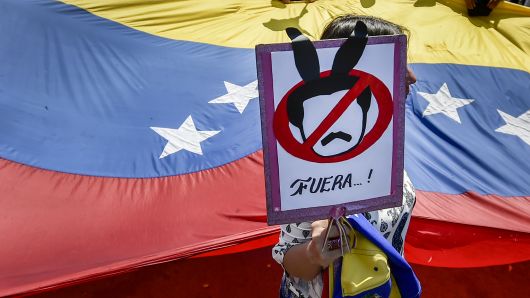 A demonstrator holds a placard as she takes part in a protest of Venezuelans against the government of President Nicolas Maduro at the Simon Bolivar International bridge in Cucuta, Colombia, on the border with Venezuela, on February 15, 2019.