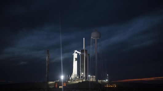 A SpaceX Falcon 9 rocket with the company's Crew Dragon spacecraft onboard is seen illuminated on the launch pad by spotlights at Launch Complex 39A as preparations continue for the Demo-1 mission at the Kennedy Space Center in Florida.