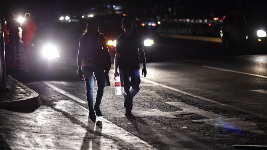 A couple walks along a street during a power cut in Caracas on March 7, 2019. - The government of Nicolas Maduro denounced a 'sabotage' against the main electric power dam in the country, after a massive blackout left Caracas and vast regions of Venezuela in the darkness.