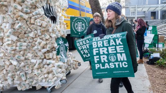 A protestor walks past a caricature made of coffee cups outside of the Starbucks Annual Shareholders Meeting at McCaw Hall, on March 21, 2018 in Seattle, Washington.