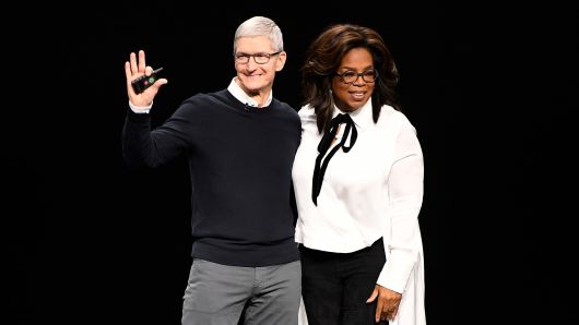 Tim Cook, chief executive officer of Apple Inc., waves while onstage with Oprah Winfrey, chief executive officer of Oprah Winfrey Network LLC, during an event at the Steve Jobs Theater in Cupertino, California, U.S., on Monday, March 25, 2019.