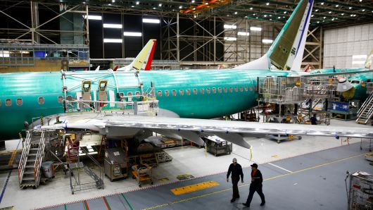Two workers walk under the wing of a 737 Max aircraft at the Boeing factory in Renton, Washington, March 27, 2019.