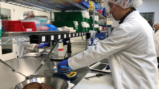 Impossible Foods product development associate scientist Kyle Okada measures plant-based burgers tailor-made for Burger King at a facility in Redwood City, California, U.S. on March 26, 2019.